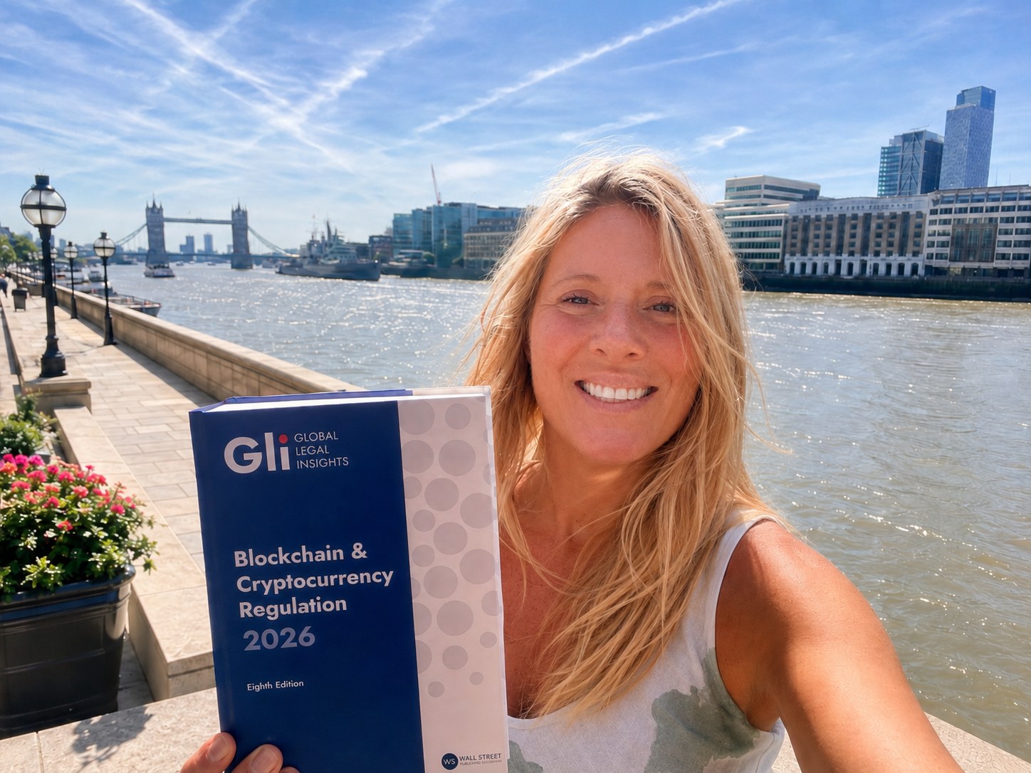 Erica Stanford holding Global Legal Insights Blockchain and Cryptocurrency Regulation 2026, to which she contributed