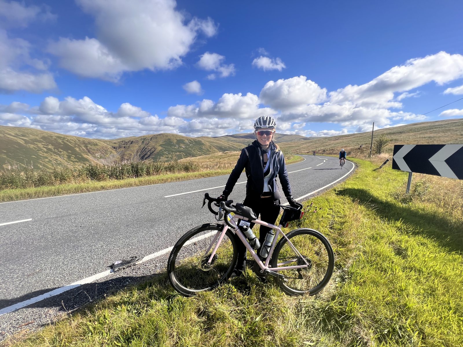 Erica Stanford with her bike on a road through the Scottish hills on the Land's End to John O'Groats ride