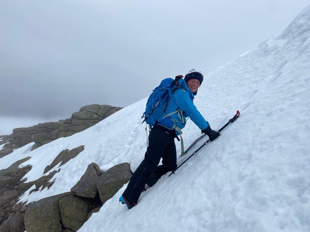 Erica Stanford traversing a steep snow slope with ice axe and poles on a winter mountain skills course in Scotland